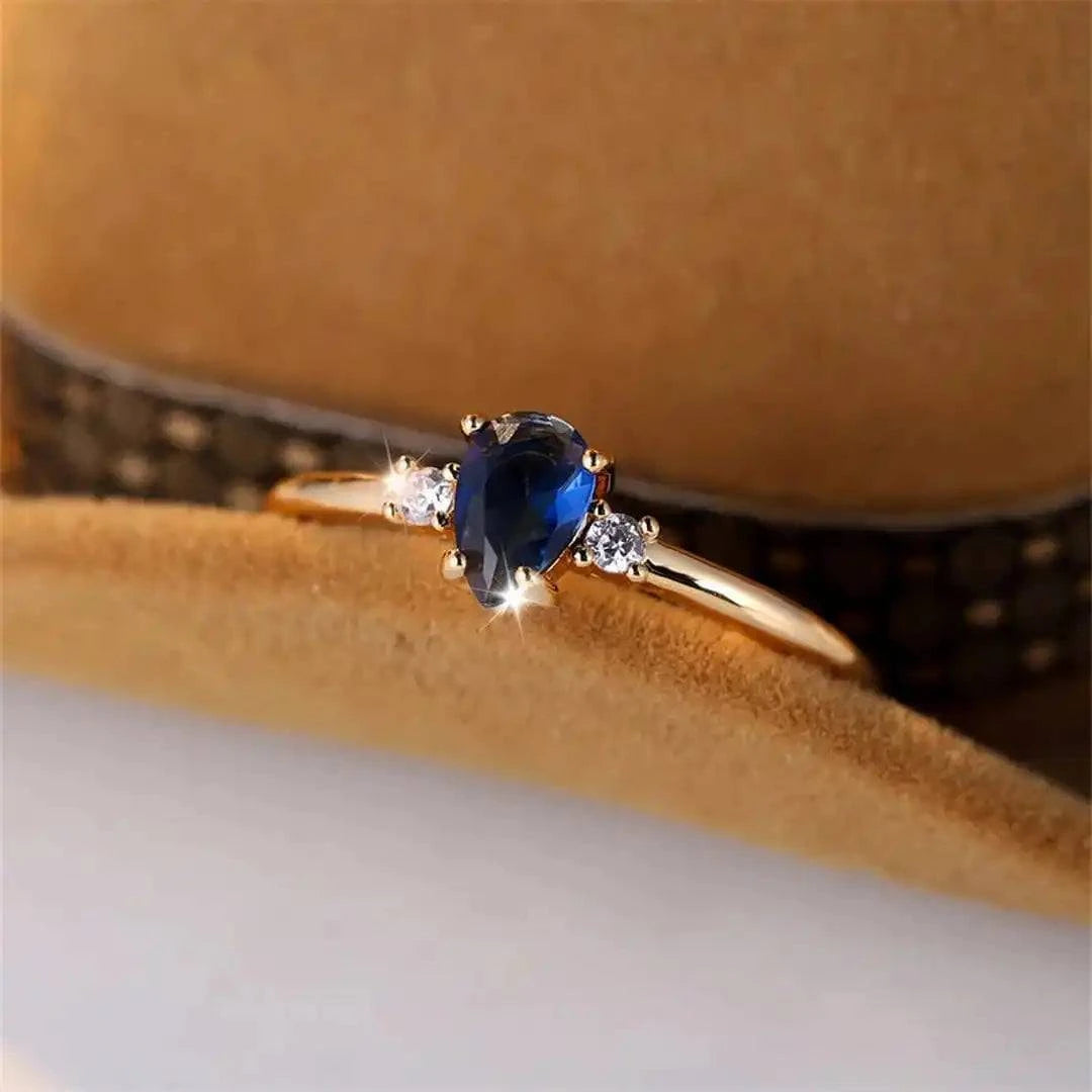 Bague minimaliste en or avec un saphir royal en forme de poire, signée Danoir Paris, vue de face sur fond blanc.