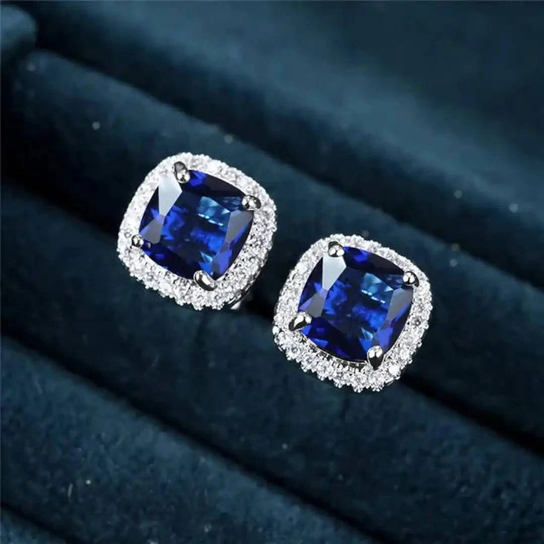 Boucles d'oreilles carrées Saphir Danoir Paris en argent, avec pierre précieuse bleue, visibles en gros plan.