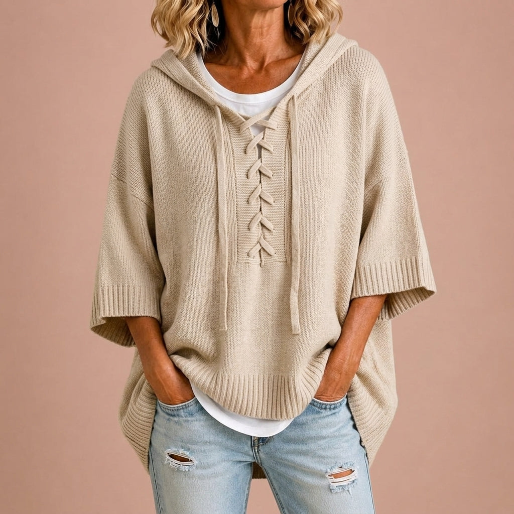 Femme portant un poncho en maille avec capuche Danoir Paris, vêtement décontracté et confortable, en train de changer de tenue.