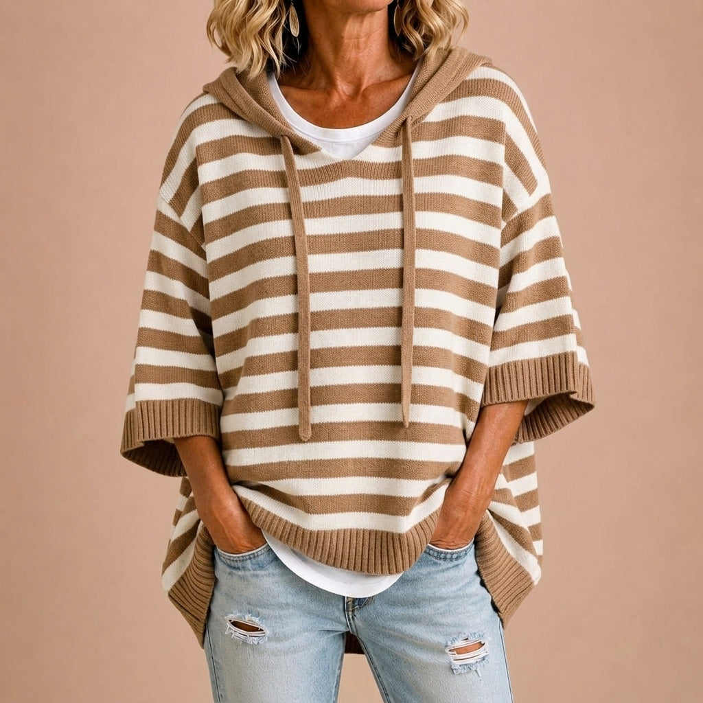 Femme portant un poncho en maille rayée avec capuche Danoir Paris, vêtement confortable et tendance.