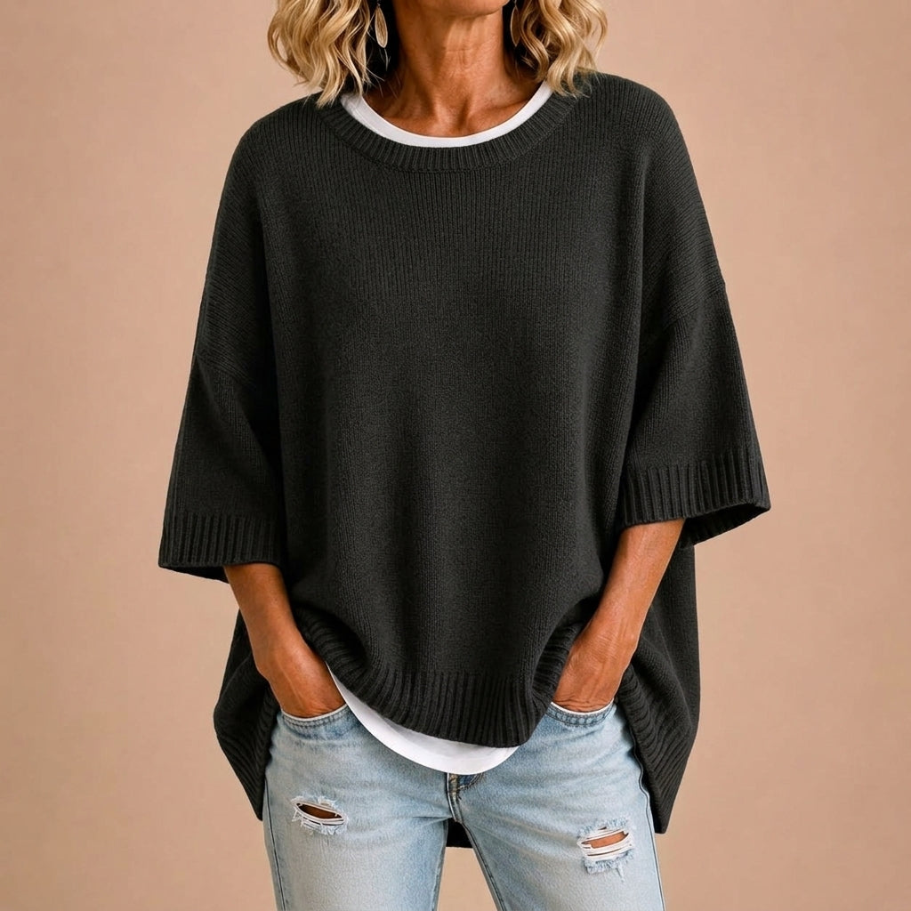 Femme portant un poncho en maille STEFANIA de Danoir Paris, en train de changer de vêtement.