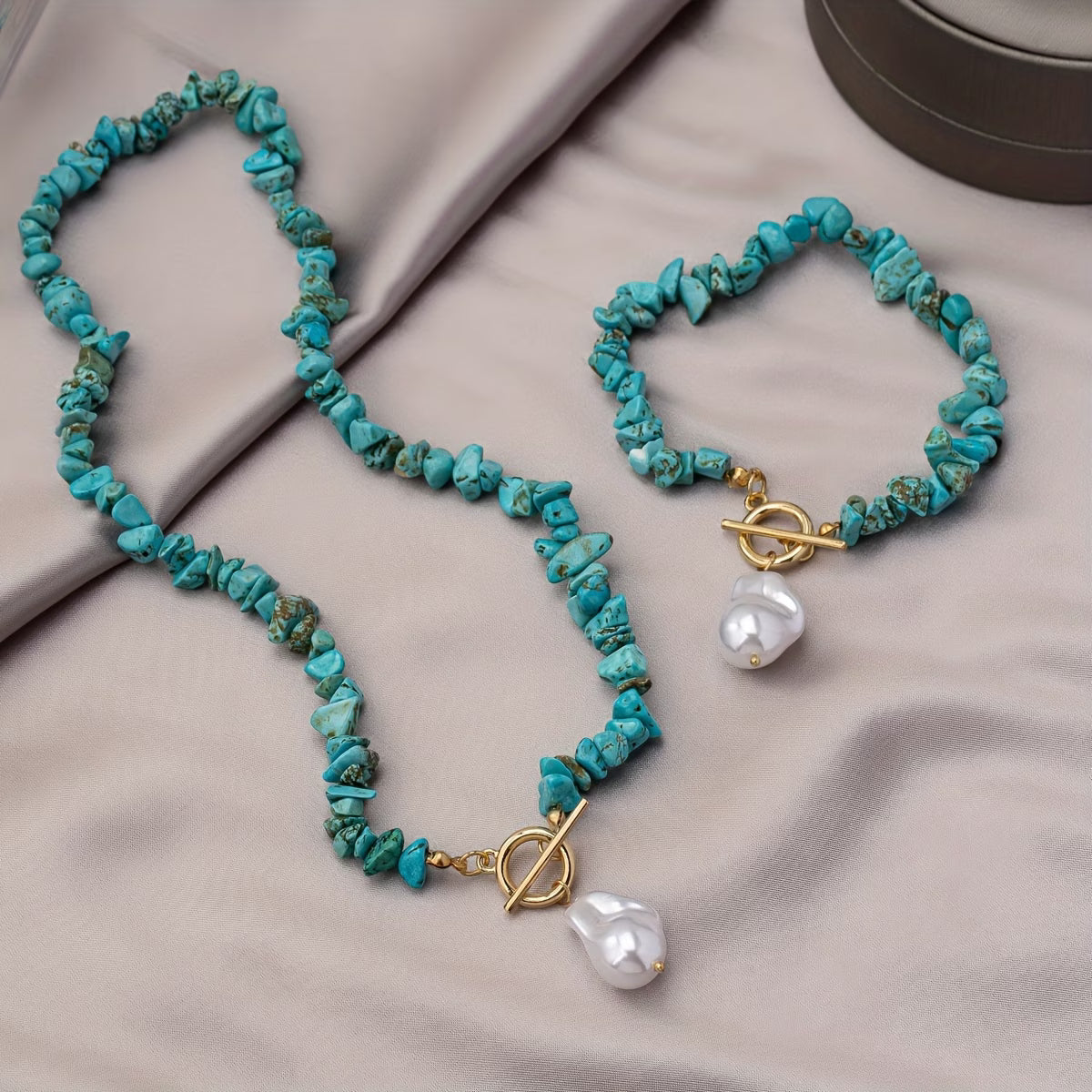 Ensemble de collier et bracelet en turquoise et perles de Danoir Paris, élégant et sophistiqué, porté sur une surface blanche.