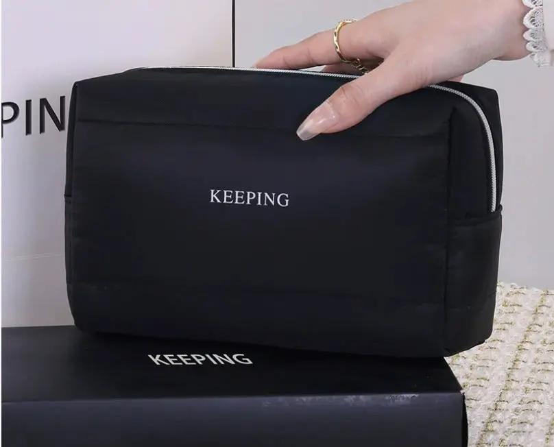 Trousse de toilette Danoir Paris avec compartiments, en tissu noir, pour ranger produits de beauté et accessoires de voyage.