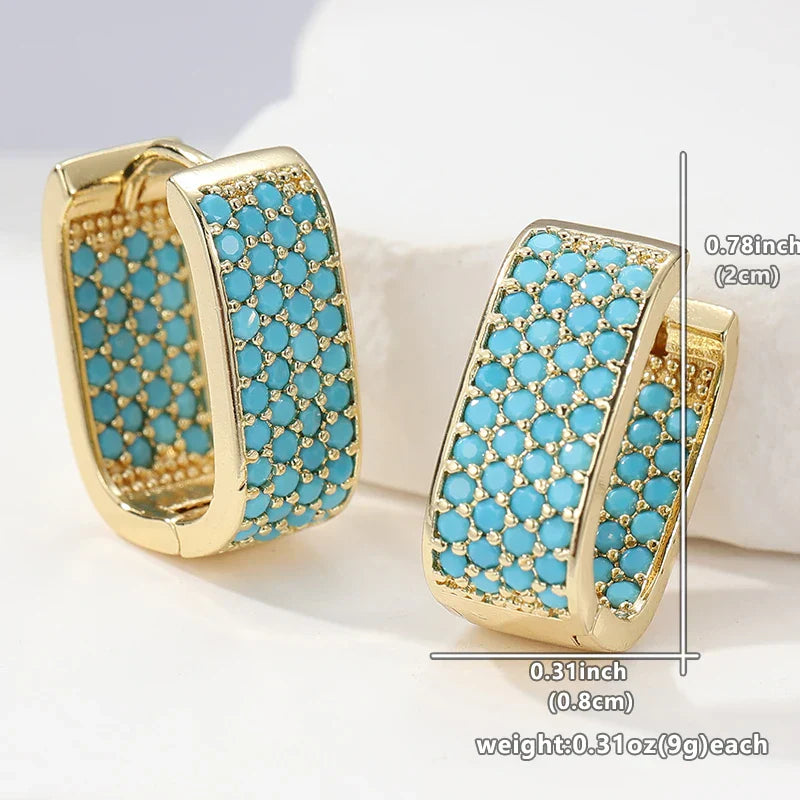 Boucles d'oreilles créoles en or avec pierre turquoise de la marque Danoir Paris, visibles en gros plan.