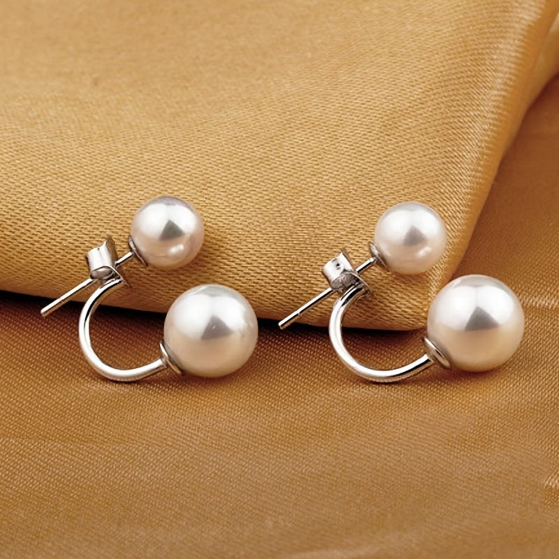 Boucles d'oreilles statement à double perle de Danoir Paris, élégantes et sophistiquées, visibles en gros plan sur un fond neutre.