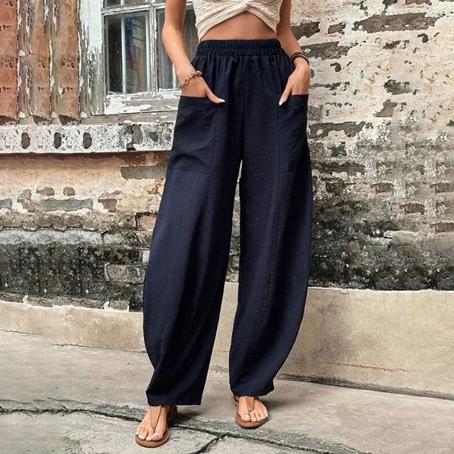Pantalons fluides gris Vanna de Danoir Paris, coupe élégante, tissu léger, porté avec une blouse blanche.