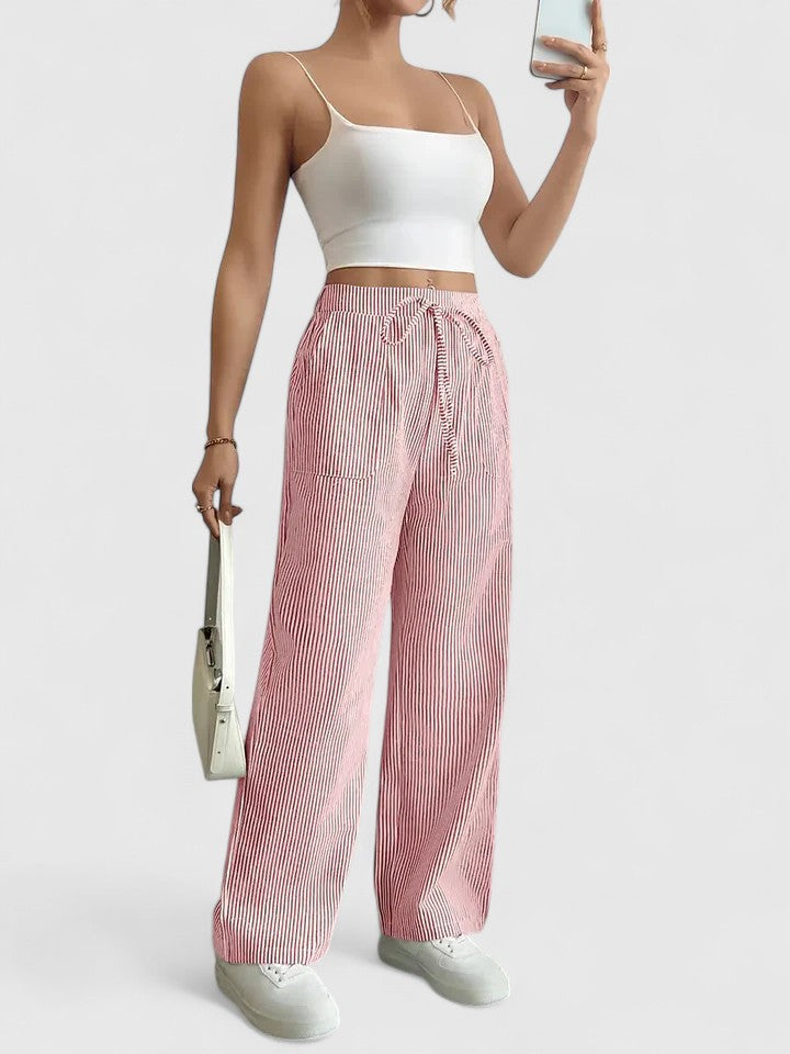 Pantalon large élégant Dominique de Danoir Paris, en tissu fluide rose, porté avec une blouse blanche, vue de face.
