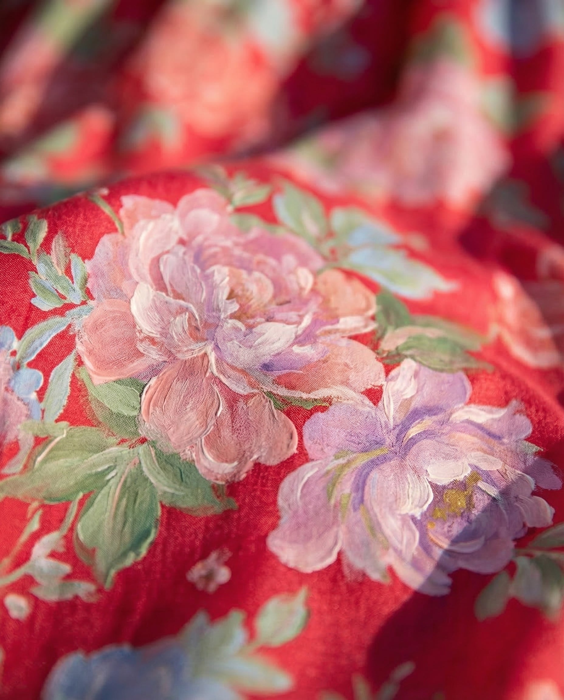 Robe fleurie Minelda de Danoir Paris avec col en V, tissu rouge avec motif floral, portée élégante et légère.