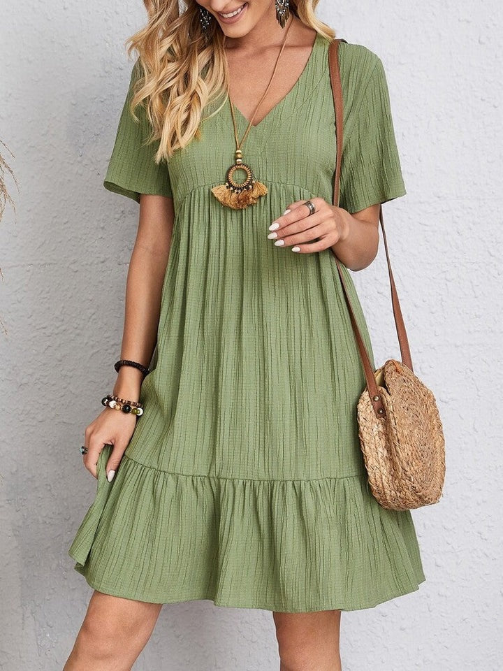 Robe élégante Danoir Paris Aisha, couverture du ventre en tissu vert, silhouette fluide et style sophistiqué.