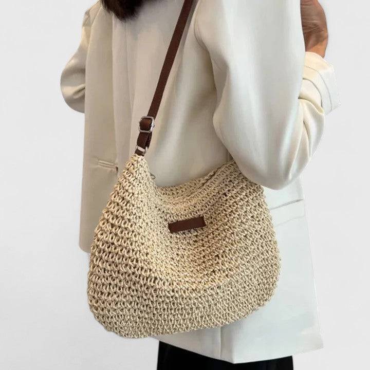 Sac Kathy élégant de Danoir Paris, en cuir noir avec poignée en métal et design sophistiqué, posé sur une surface en bois.