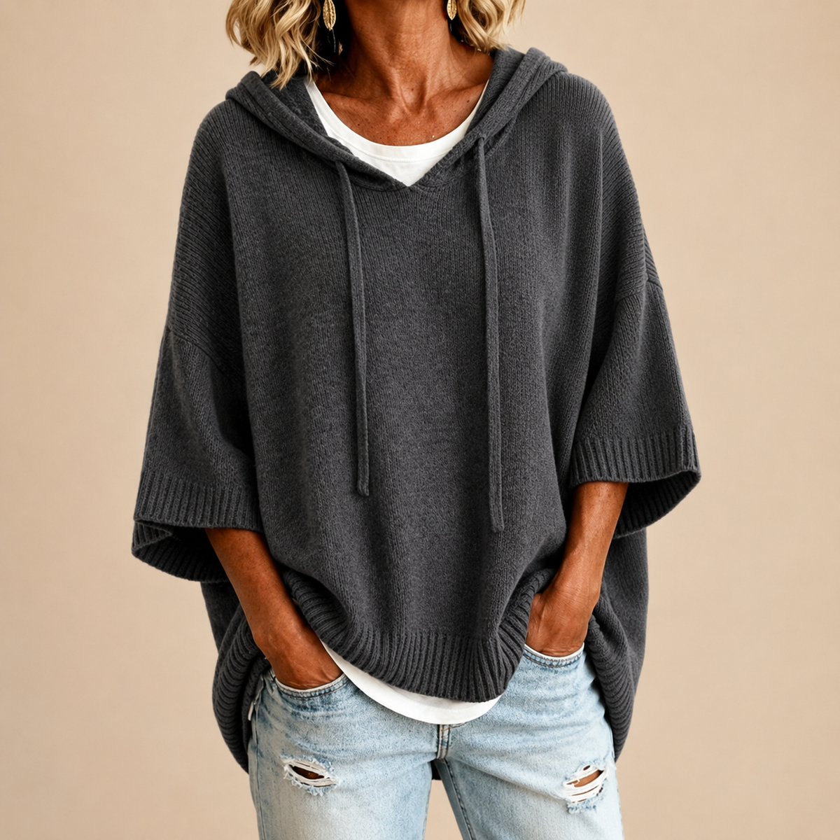 Poncho en maille Danoir Paris MIRELLA™ avec capuche, tissu doux et chaud, porté sur un fond neutre.