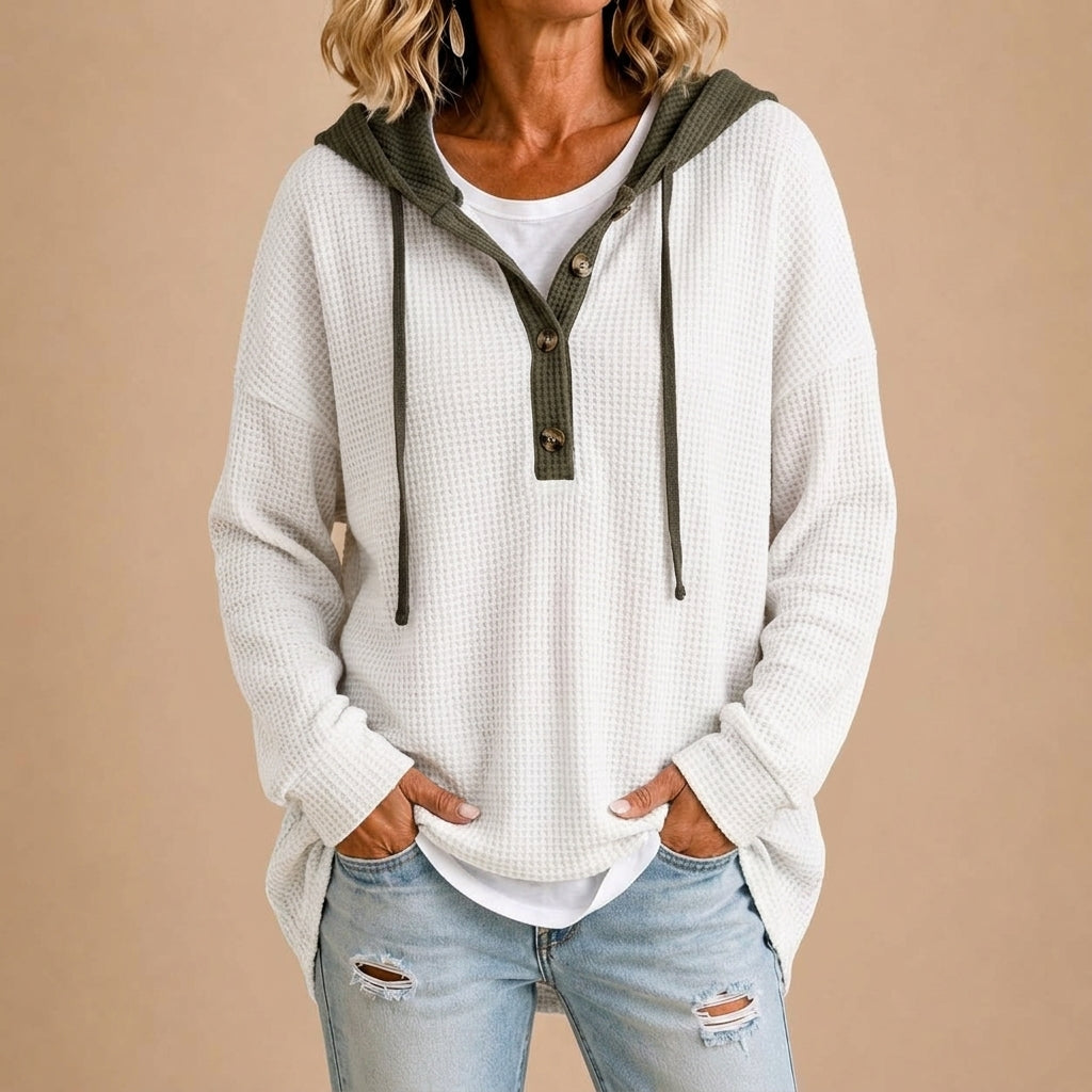 Poncho en maille Danoir Paris avec capuche, boutons et design élégant, porté par une femme dans une tenue décontractée.