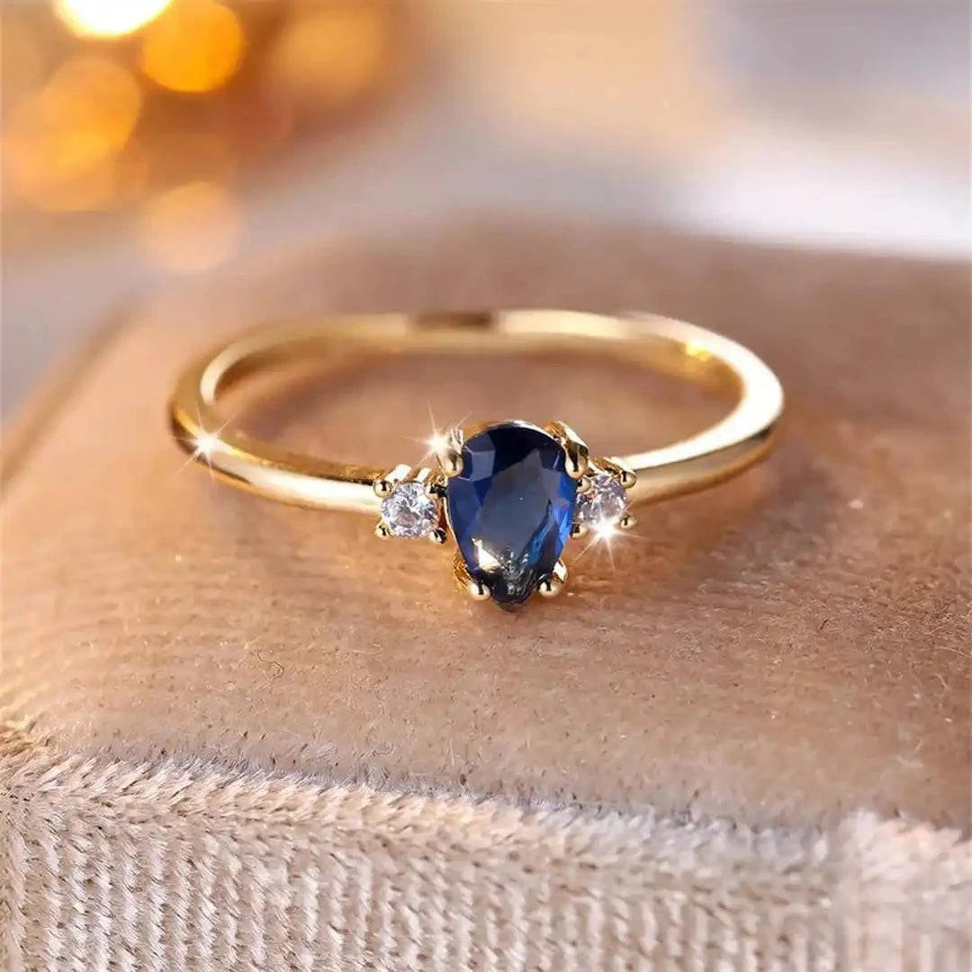 Bague minimaliste en or avec une pierre saphir royal en forme de poire, design élégant par Danoir Paris