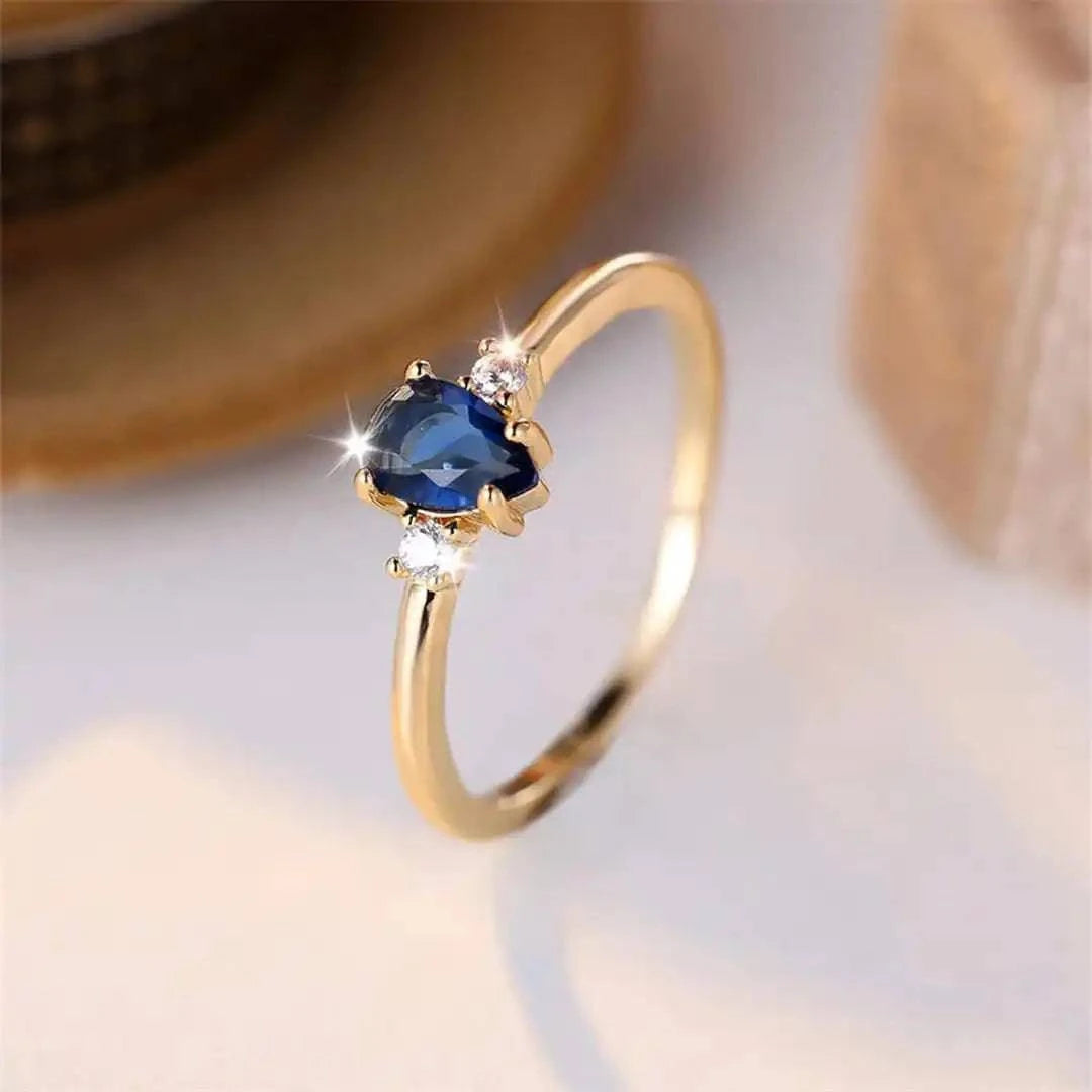 Bague minimaliste en or avec saphir royal en forme de poire, design élégant de Danoir Paris, vue en gros plan.
