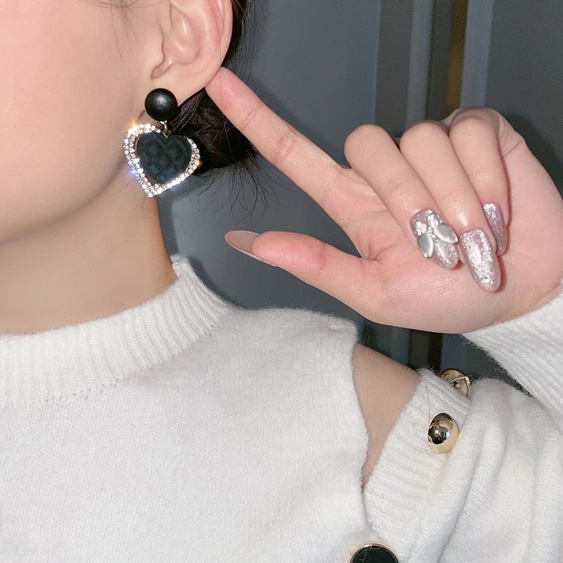 Boucles d'oreilles en or noir en forme de cœur de la marque Danoir Paris, avec design élégant et brillant visible sur l'image.