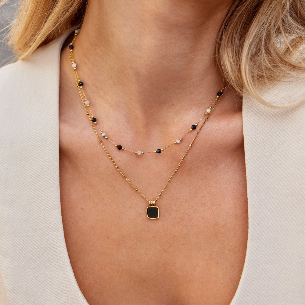 Collier à couches Danoir Paris avec pierres colorées, perles et détails élégants, porté sur un fond neutre.