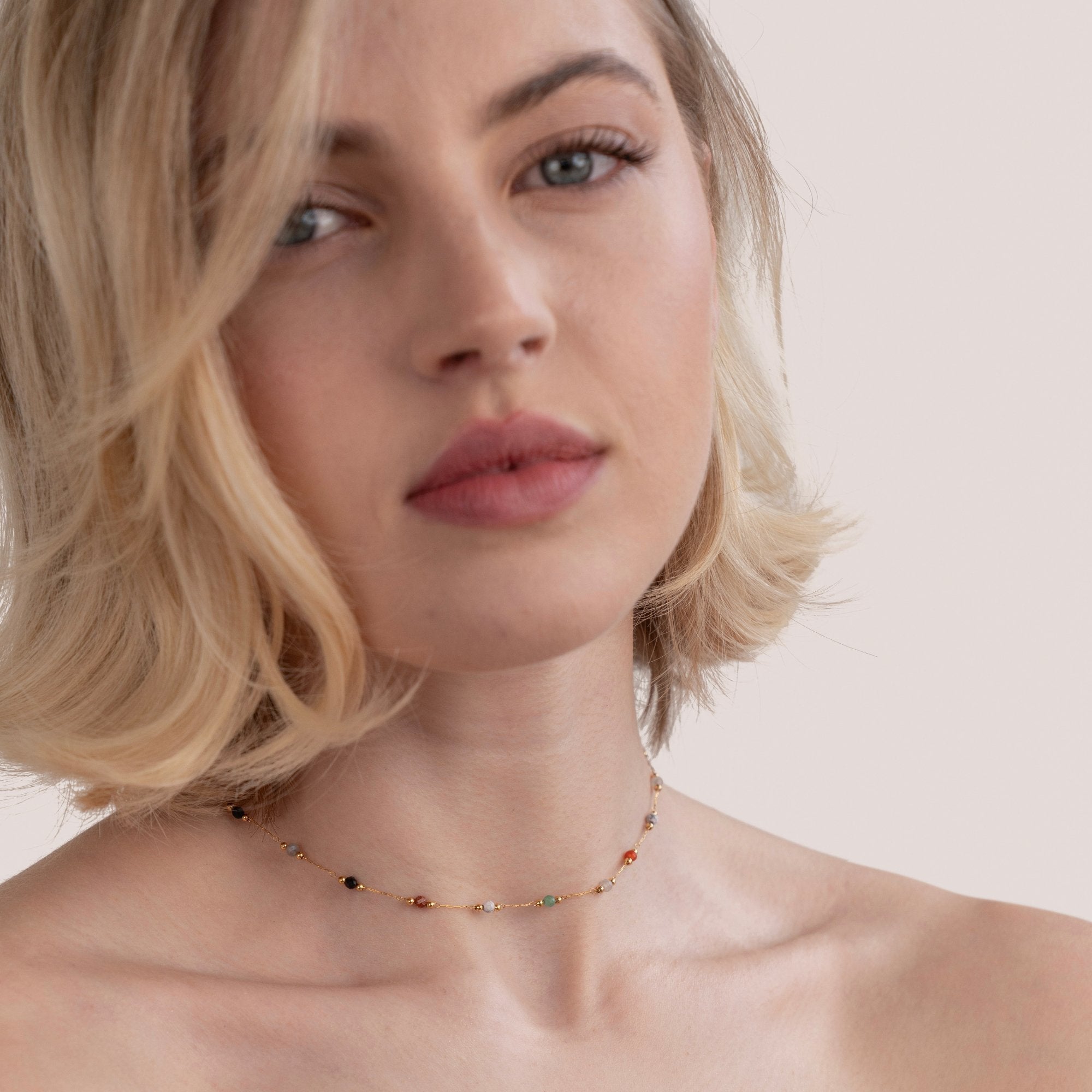 Collier minimaliste avec pierre de Danoir Paris, chaîne fine et pendentif en pierre naturelle, porté sur un fond neutre.