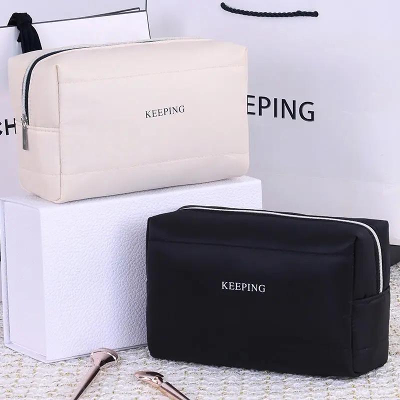 Trousse de toilette Danoir Paris en tissu noir avec fermeture éclair et poches pour accessoires de beauté.