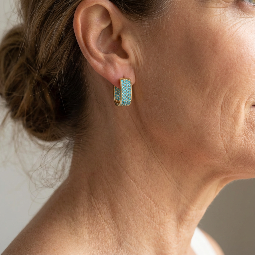 Boucles d'oreilles hoops dorées avec pierre turquoise Crush par Danoir Paris, visibles en gros plan.