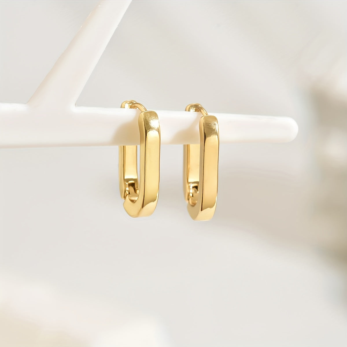 Boucles d'oreilles créoles géométriques élégantes de marque Danoir Paris, en métal doré, visibles en gros plan.