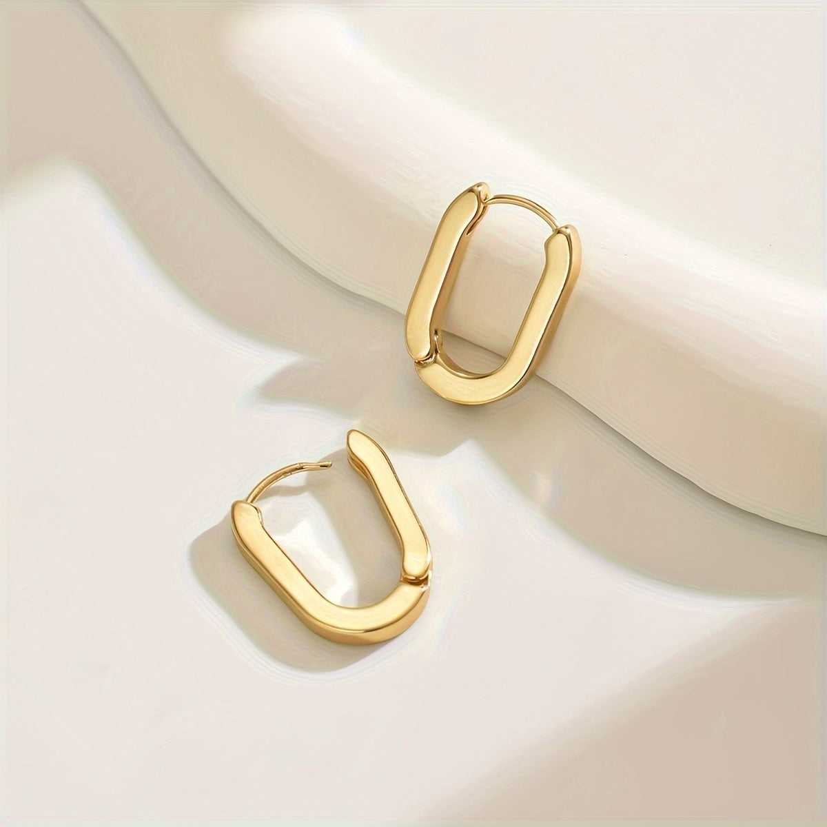 Boucles d'oreilles créoles élégantes de forme géométrique en or, par Danoir Paris, visibles en détail.