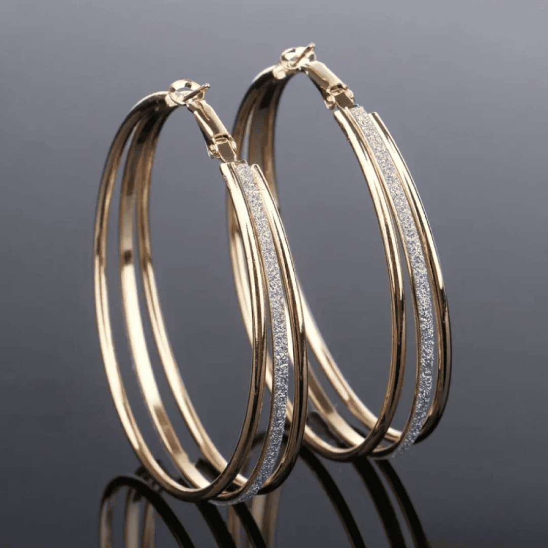 Boucles d'oreilles créoles rétro en or doré de la marque Danoir Paris, visibles en gros plan.