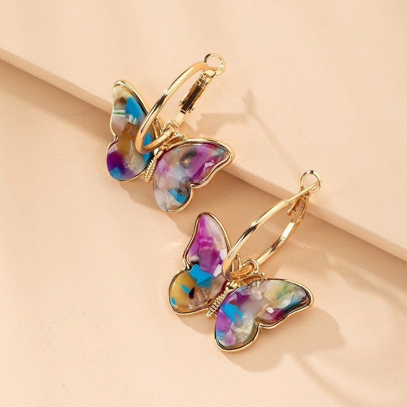Boucles d'oreilles créoles dorées avec papillons multicolores, bijoux tendance de Danoir Paris.