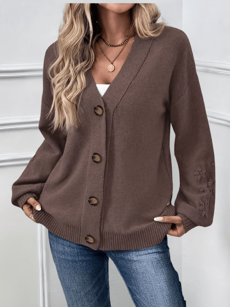 Cardigan classique élégant Hélène de Danoir Paris en rose pâle, joli détail de finition, porté sur un fond neutre.