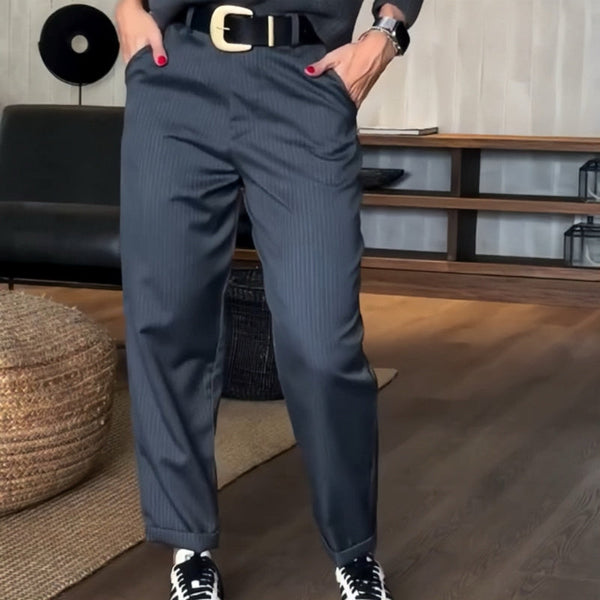 Pantalon élégant Mathilda de Danoir Paris en tissu bleu foncé, coupe polyvalente, porté avec une blouse blanche.