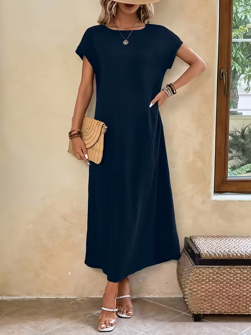 Robe longue élégante et minimaliste Margaux™ de Danoir Paris, en tissu noir, portée avec manches longues et coupe fluide.