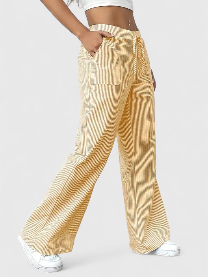 Pantalon large élégant Dominique de Danoir Paris en tissu fluide, couleur rose, porté avec une blouse blanche.