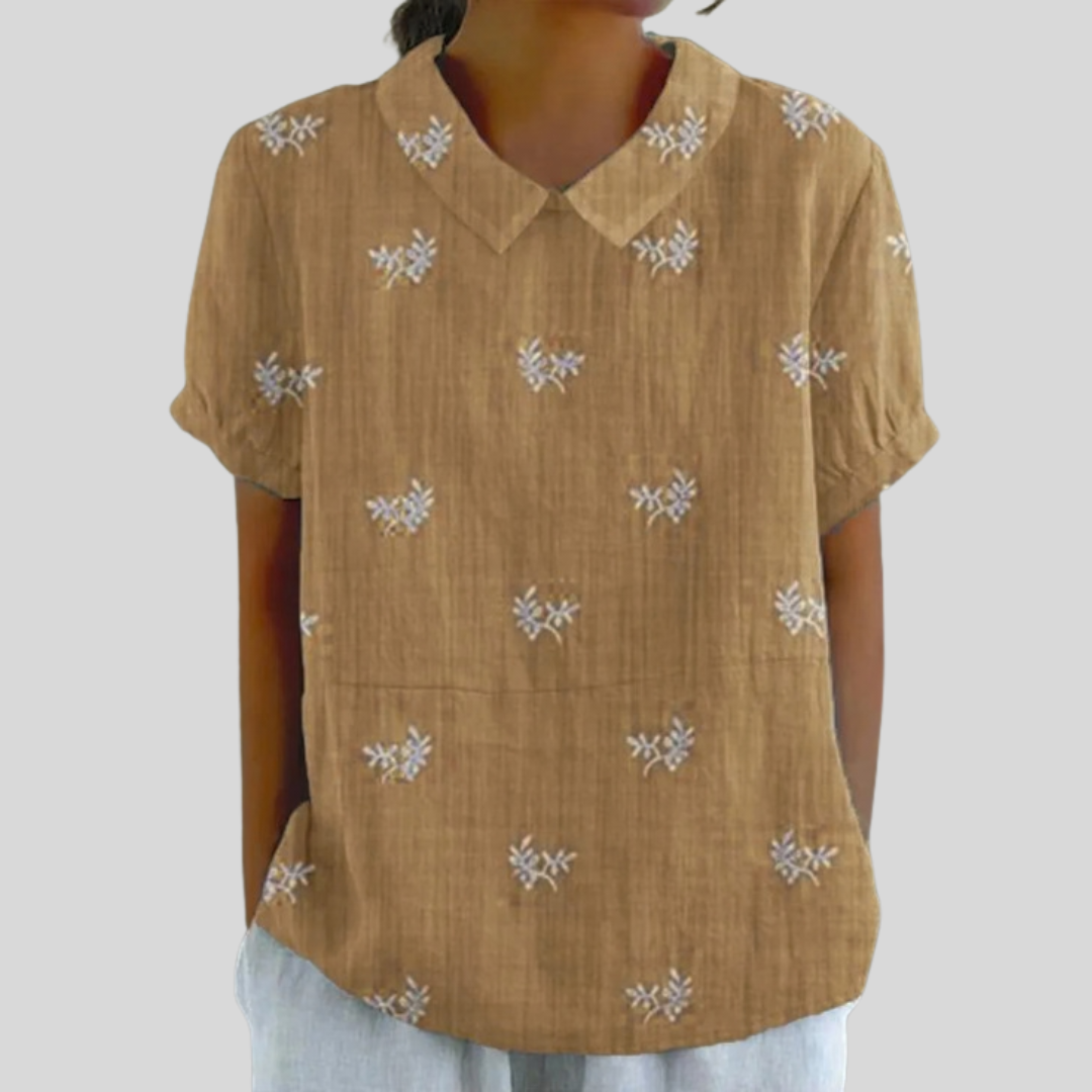 Blouse brodée discrète Geneviève de Danoir Paris, en coton léger avec détails délicats, portée sur un fond neutre.