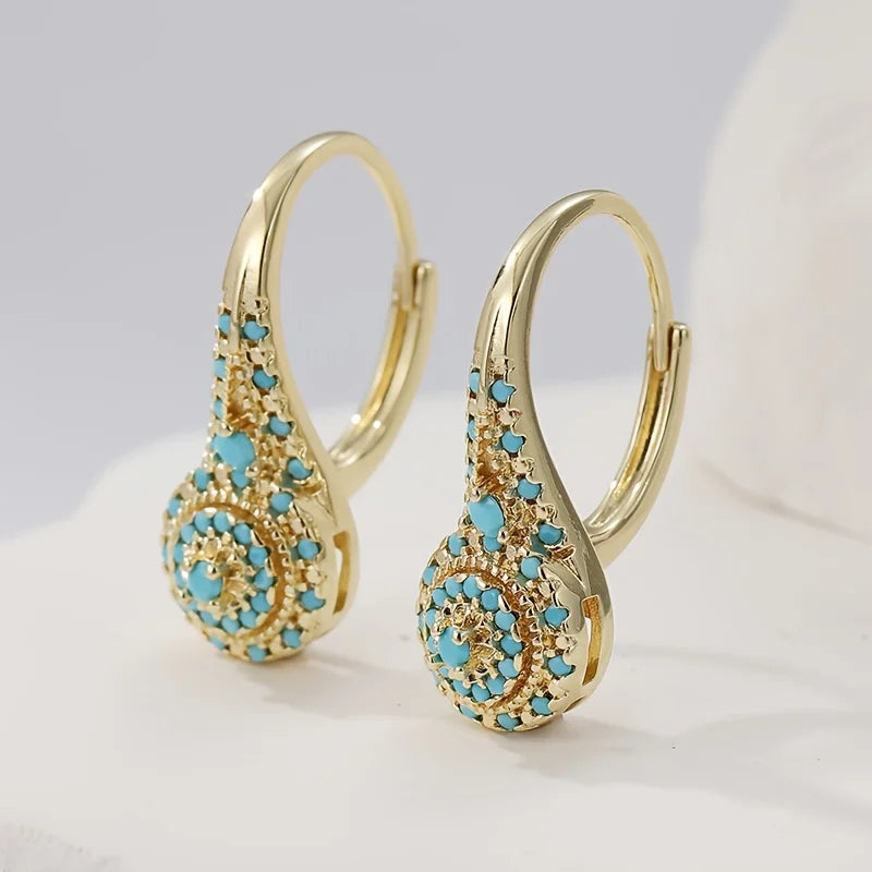 Boucles d'oreilles Danoir Paris turquoise doré en forme de fleur avec pierre turquoise brillante.