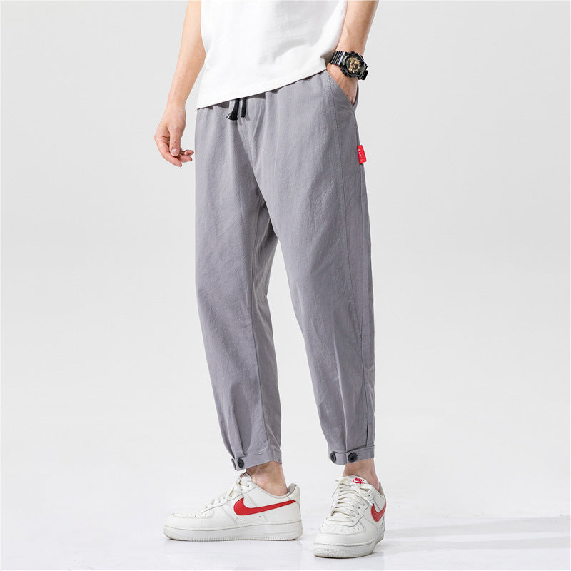 Pantalons ajustés en coton Theo de Danoir Paris, coupe moderne, tissu confortable, couleur neutre, porté avec une chemise blanche.