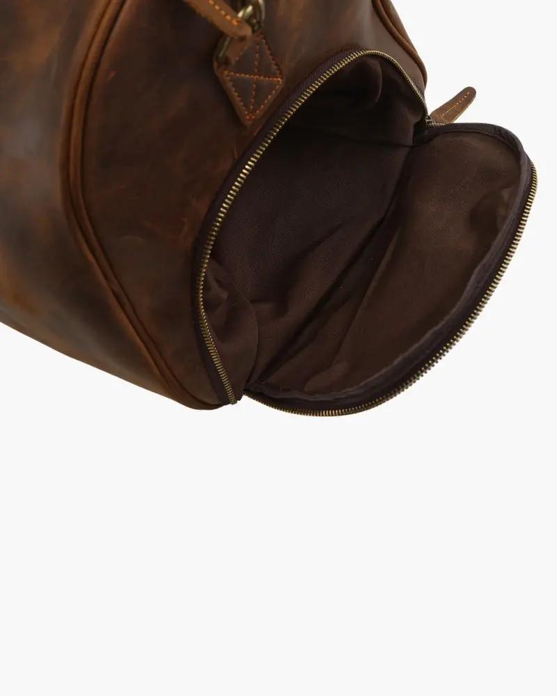 Sac de voyage en cuir marron Old Money Montague Duffle avec poignées et fermeture éclair visible.